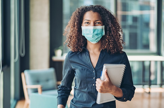 Woman wearing a face mask holding a notebook